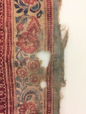 A flat textile with a red and blue floral design on a white ground is encapsulated in white net, secured with large white stitches. The next overlays two large losses in the textile and a raw edge with loose threads.