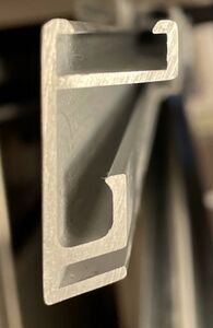 The profile (cross-section) of a metal frame. This frame includes (from the bottom up): a slot at the bottom for the glazing, a built-in spacer, a gap for the mounted artwork/backing board, and finally an opening for the corner hardware.