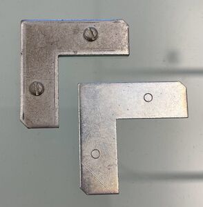 The hardware used to attach the rails of a metal frame at the corners.These are stacked on top of each other, inserted into the gap in the rail, and the screws in the top piece turned to press against the flat bottom piece.